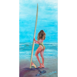 woman in a green bathing suit standing on Pipes Beach in Cardiff holding a longboard looking out at the waves
