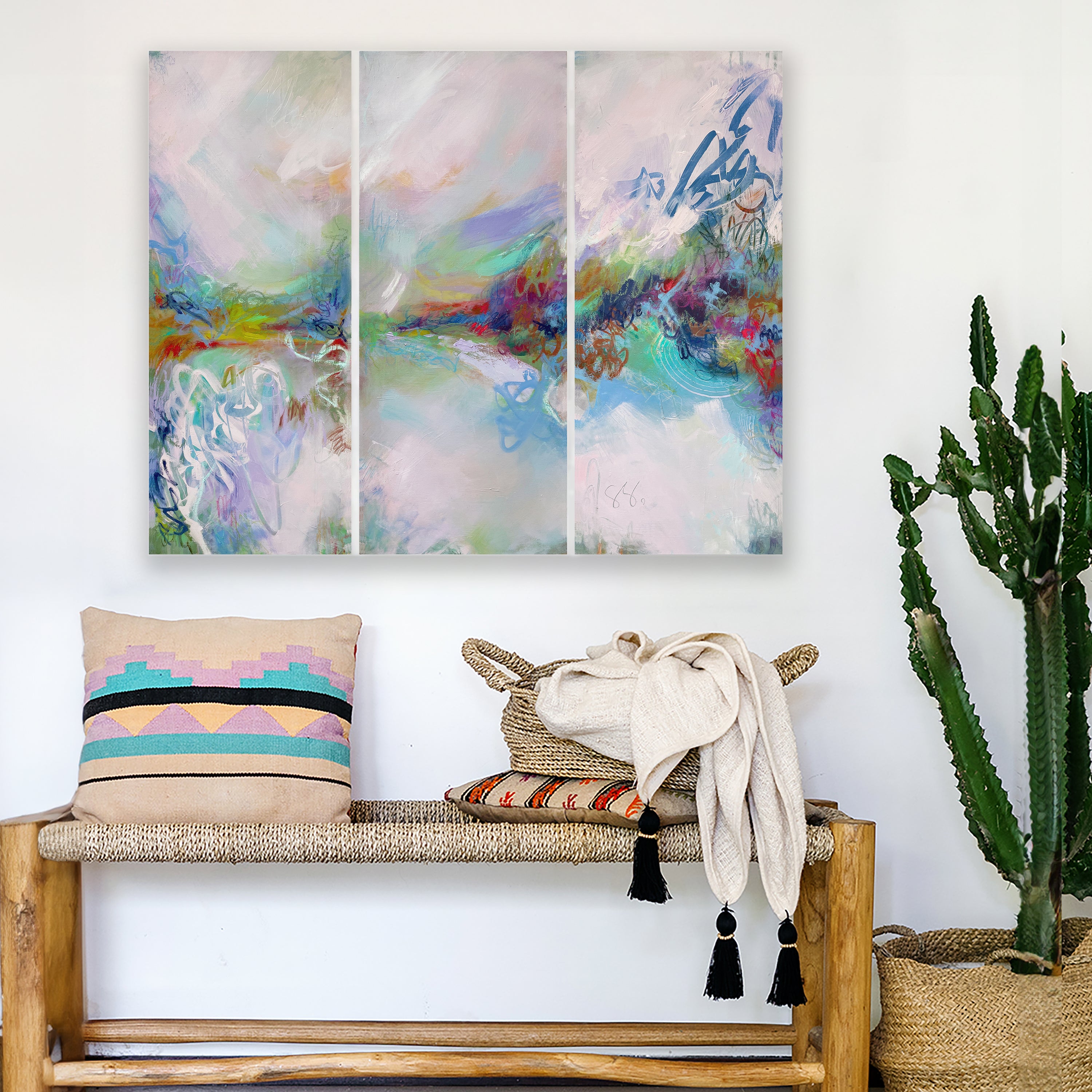 Expressive abstract landscape painting hanging over a bench and seat cushions in a boho style living room 